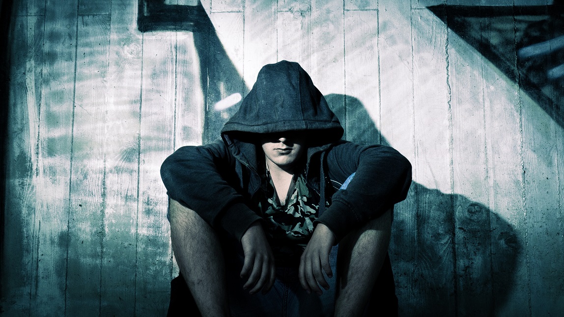 'Person Wearing Black Zip Hoodie Sitting in Front of Gray Wooden Plank Wall during Nighttime' from public domain site Pexels